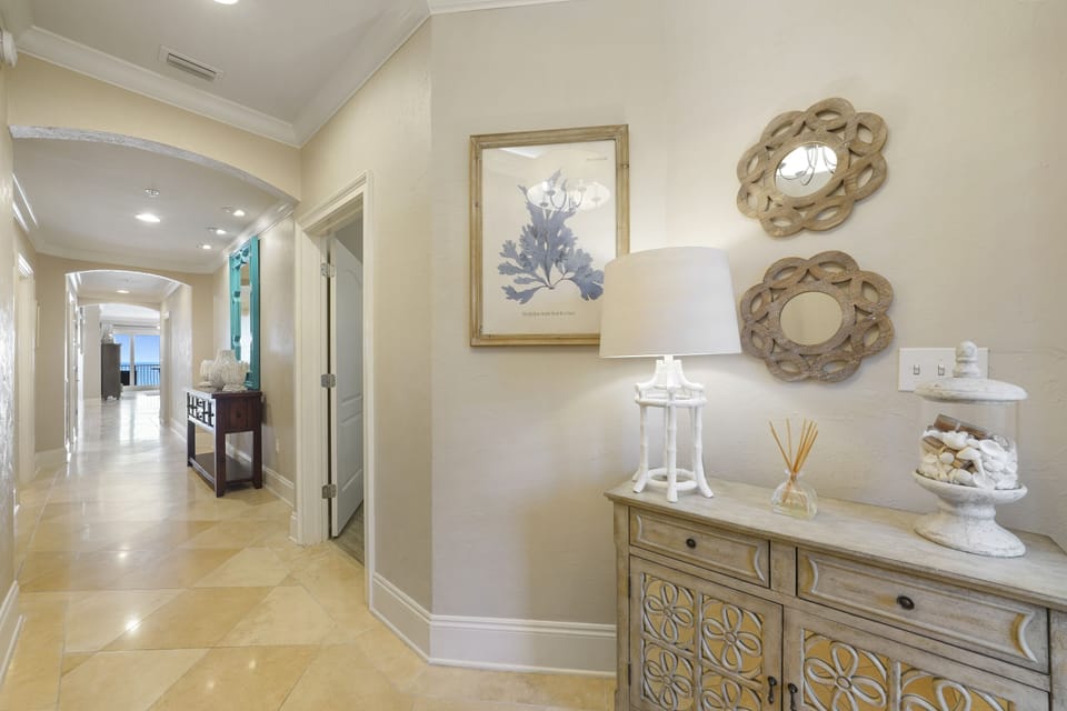 Bright and welcoming interior hallway at Adagio Unit B202 on 30A, showcasing refined coastal living with arched entryways, tile flooring, and beach inspired décor.