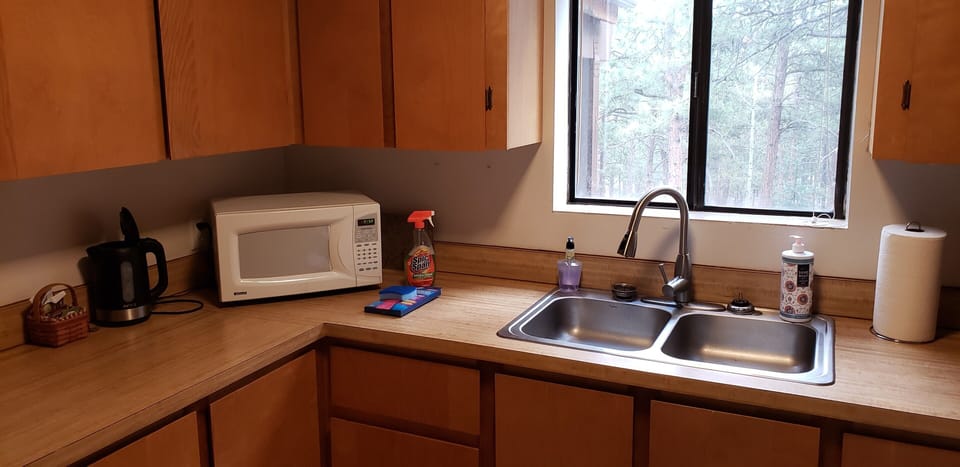 Kitchen counter with microwave and hot water pot. 