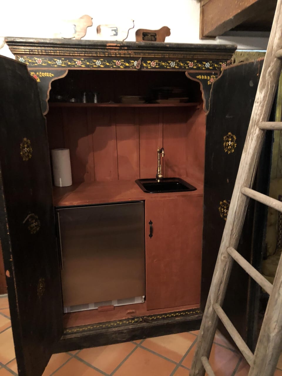 Cabin A refrigerator and sink inside black armoire
