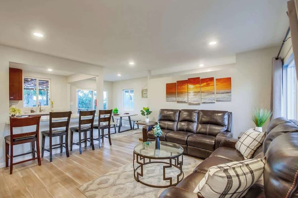 The living room offers ample seating with multiple couches, and there are comfortable bar stools at the breakfast bar for additional seating.