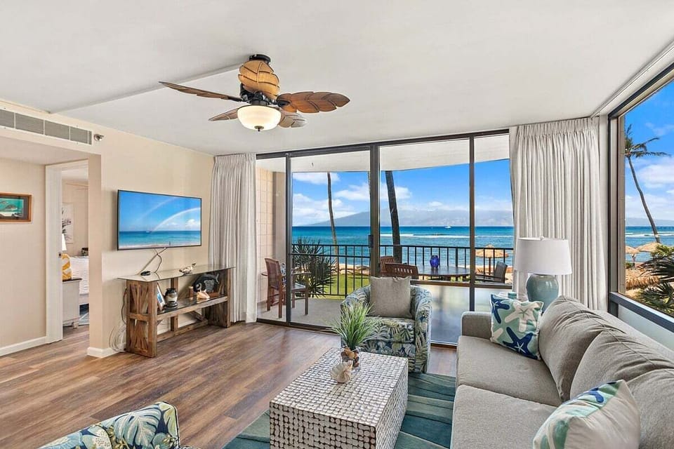 A living room with breezy décor and sliding doors that open directly to the sea.