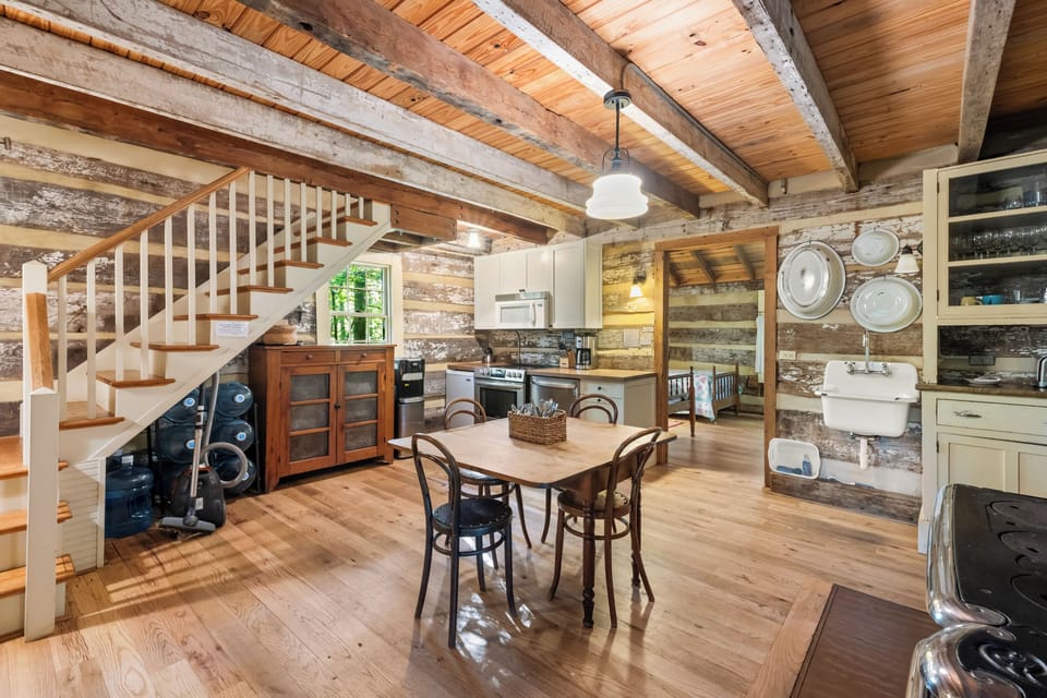 Charming farmhouse-style kitchen with cream cabinets, a vintage sink, glass-front cabinetry, and rustic log walls—blending comfort with classic cabin character.