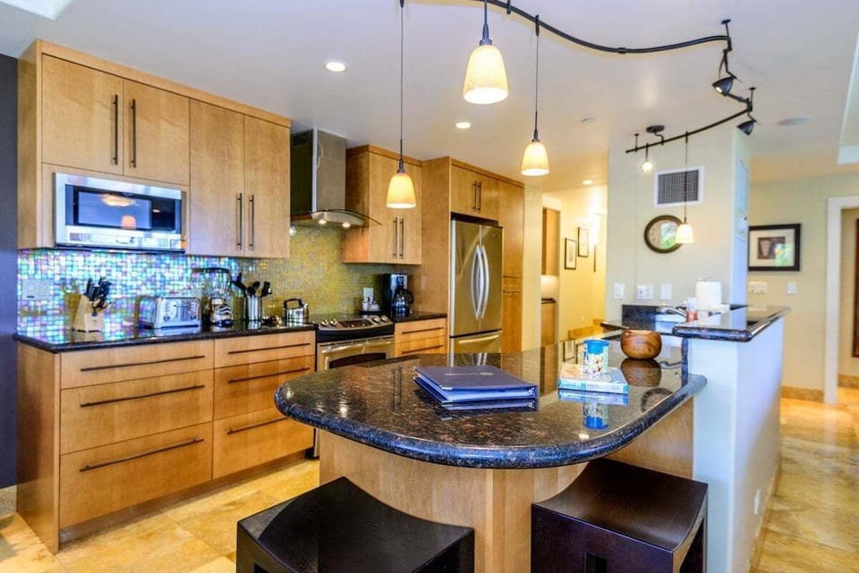 Fully equipped kitchen with granite countertops, modern appliances, and warm wood cabinetry.