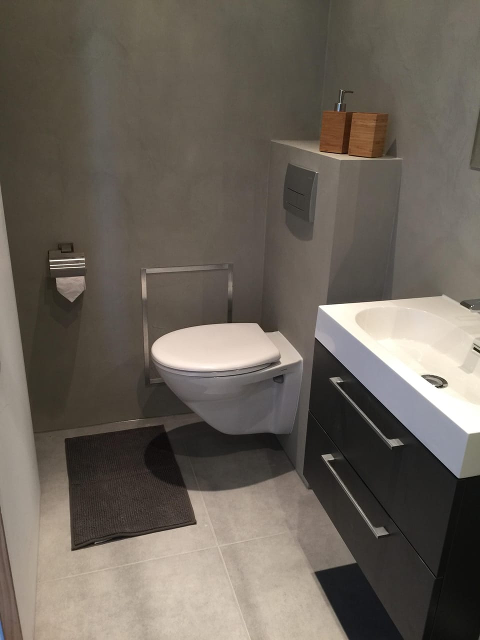 Bathroom with toilet, sink, shower, hairdryer and soap dispensers