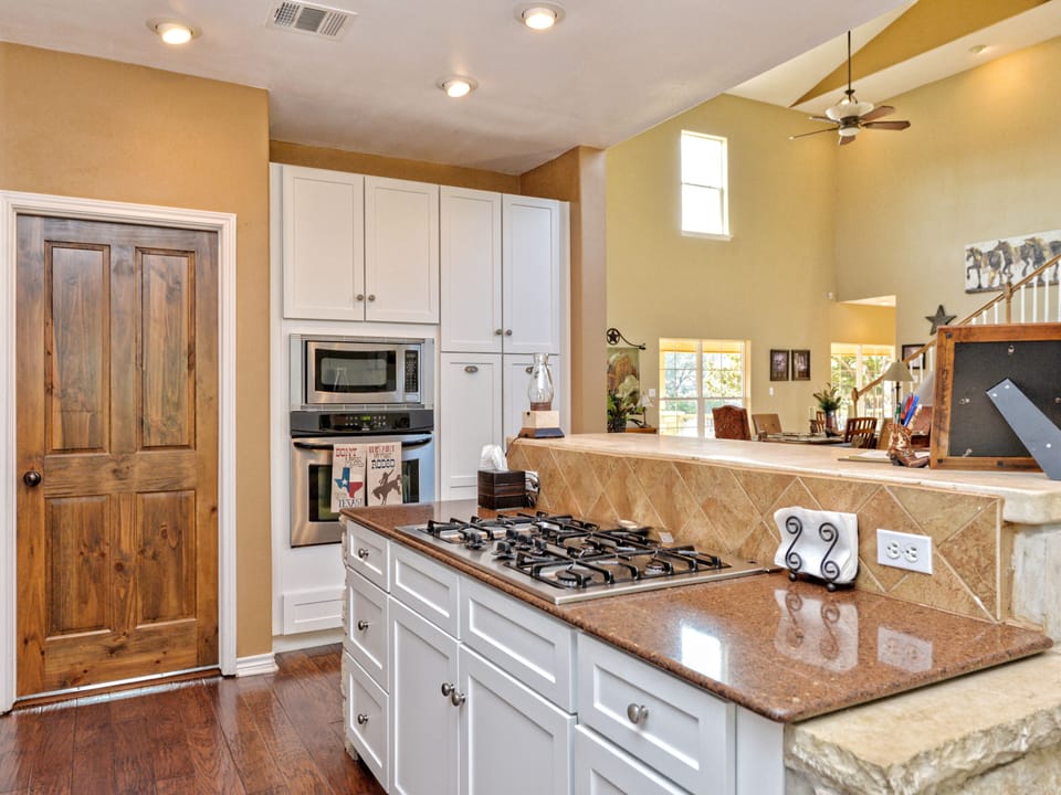 Kitchen view of gas stove top and microwave, oven and pantry.