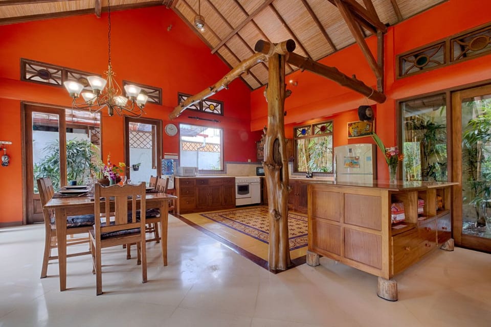 Dining table and kitchen framed in teak tree trunks. 