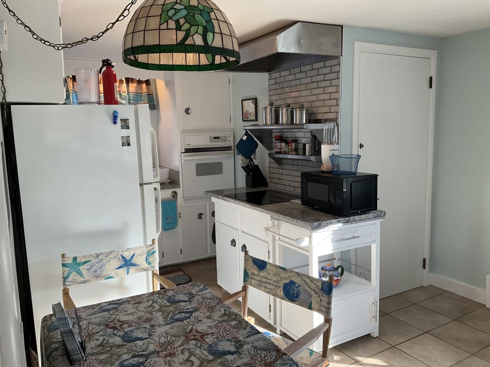 Small work in kitchen with granite countertops and stainless steel shelving.