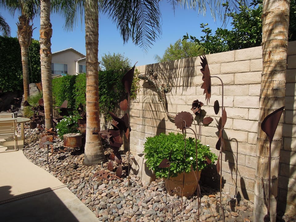 Custom metal statuary in yard. Some palm trees shown have died due to drought.
