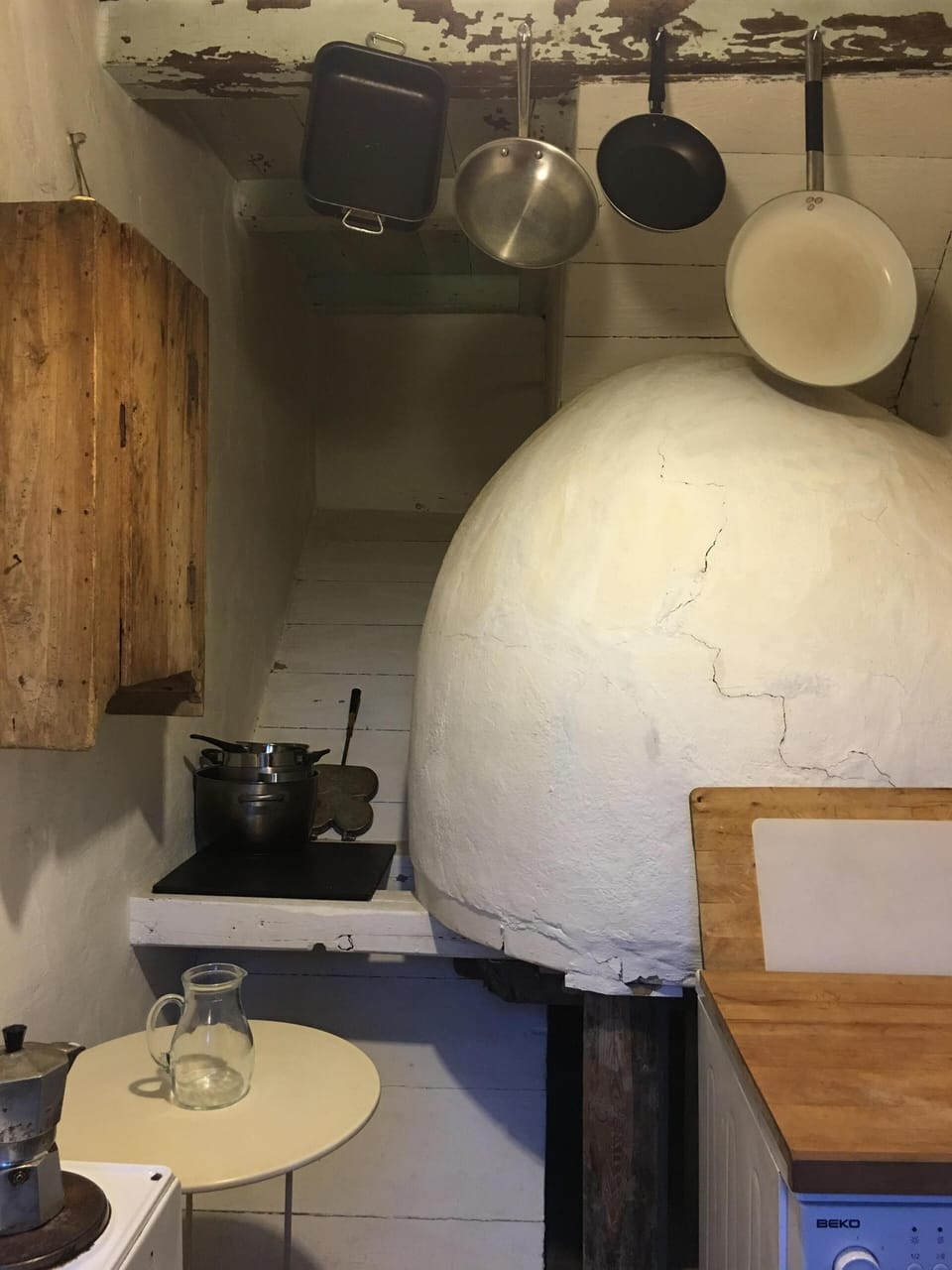 Kitchen with wood-fired pizza oven, washing machine, stove, pots and pans