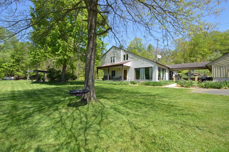 Front of the home with tree swing and yard