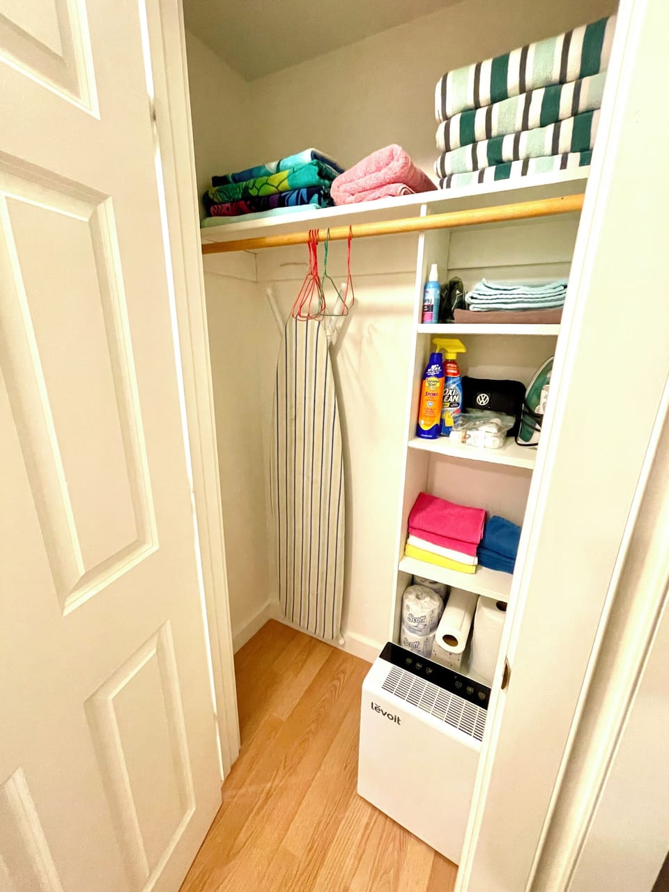 Hallway closet with bath & beach towels, iron & ironing board, & extra supplies.