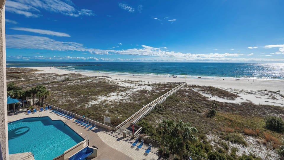 Take in the beautiful view from your balcony, overlooking the inviting pool and the expansive shoreline beyond