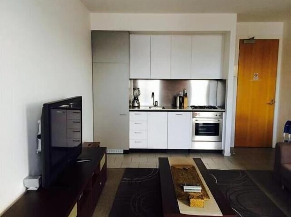 Kitchen with stone bench and hidden dishwasher and bar fridge.