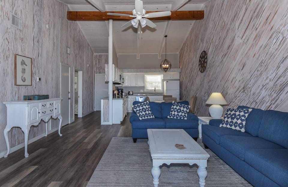 Living room with blue seating and white tables