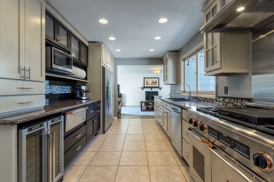 Fully stocked chef’s kitchen with modern appliances, wine fridge, and spacious granite counters—perfect for cooking and gathering.