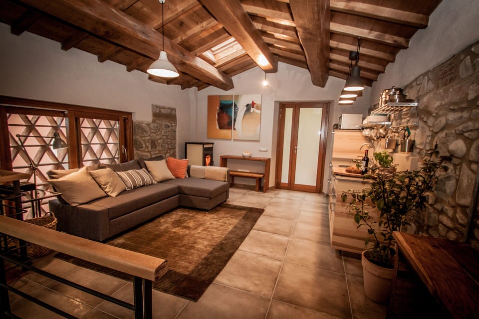 Chestnut beamed open plan sitting room with kitchen and view of pool and garden.
