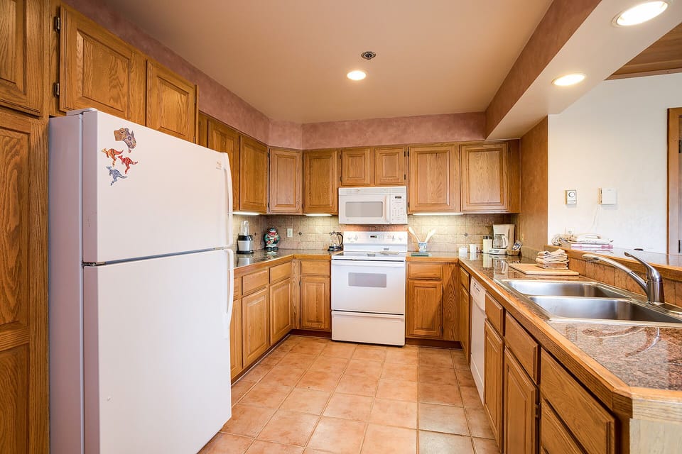 A fully equipped kitchen with oak cabinetry, modern appliances, and granite counters where you can prepare your favorite meals in comfort.