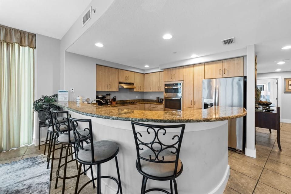 Your gourmet kitchen features granite counters, premium appliances, and a curved breakfast bar perfect for morning coffee or casual meals.