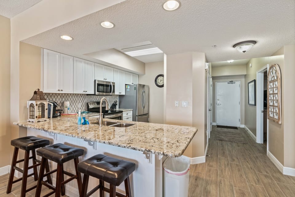 Kitchen with view of entry door and hallway that leads to two front bedrooms.