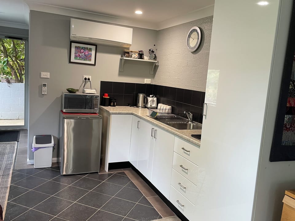 Kitchenette with microwave, toaster, kettle, fridge, crockery, cutlery, glasses.