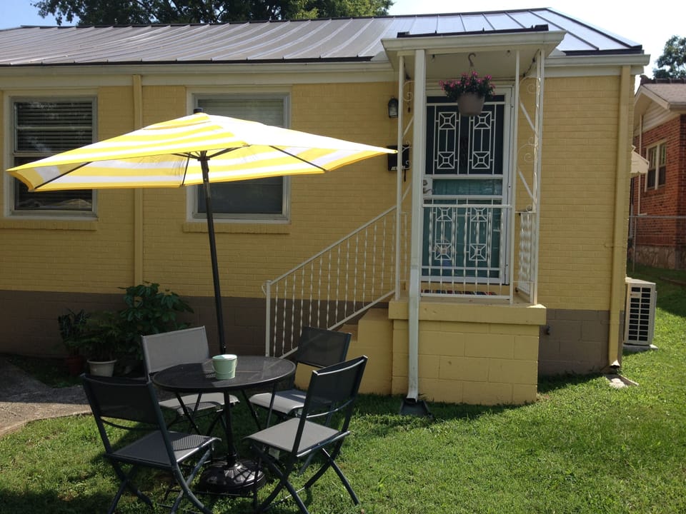 View of front with table, chairs, and umbrellas for enjoying outside