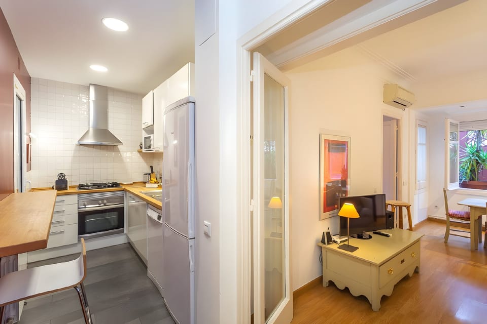 Step from the modern, fully equipped kitchen into a warm and inviting living space, which connects to an indoor patio with a washing machine.