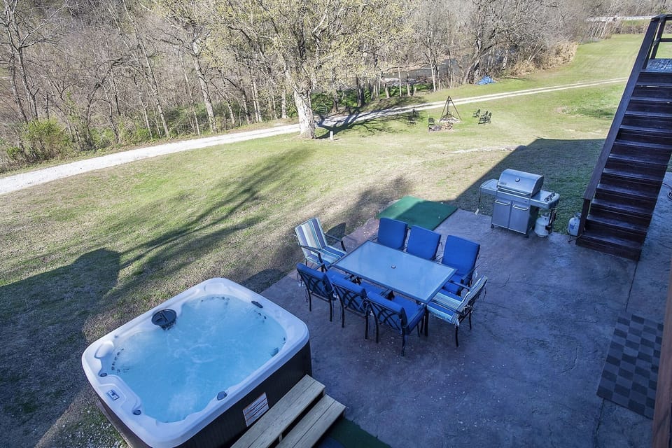 patio view with hot tub, seating area and grill