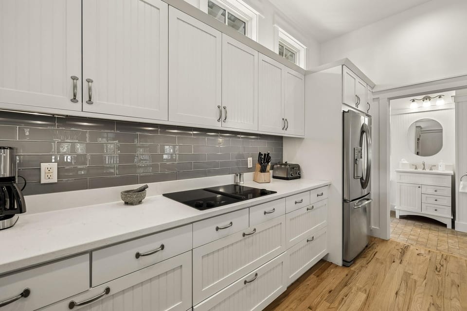 White beadboard cabinetry lines the kitchen with a gray subway tile backsplash and stainless steel appliances.