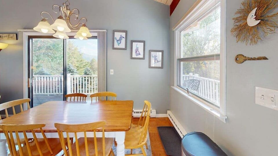 Dining area with table seating and large windows overlooking the deck and surrounding scenery.
