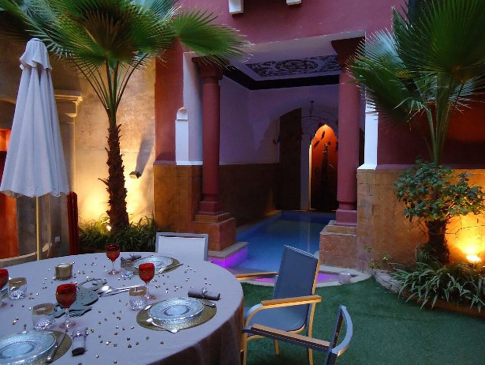Romantic dinner table set at poolside within courtyard.