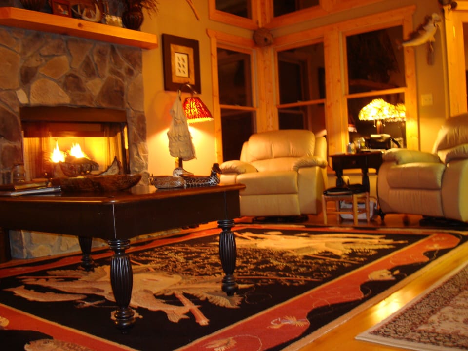 Great room at night, leather sofa, recliners, vaulted ceiling, fireplace, big TV