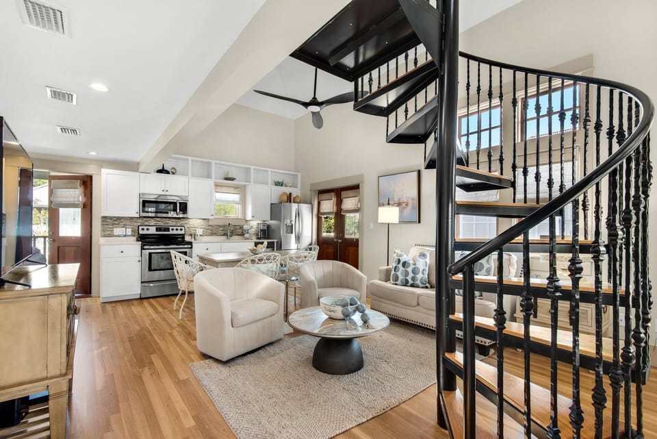 Bright open living room with cozy seating and spiral staircase