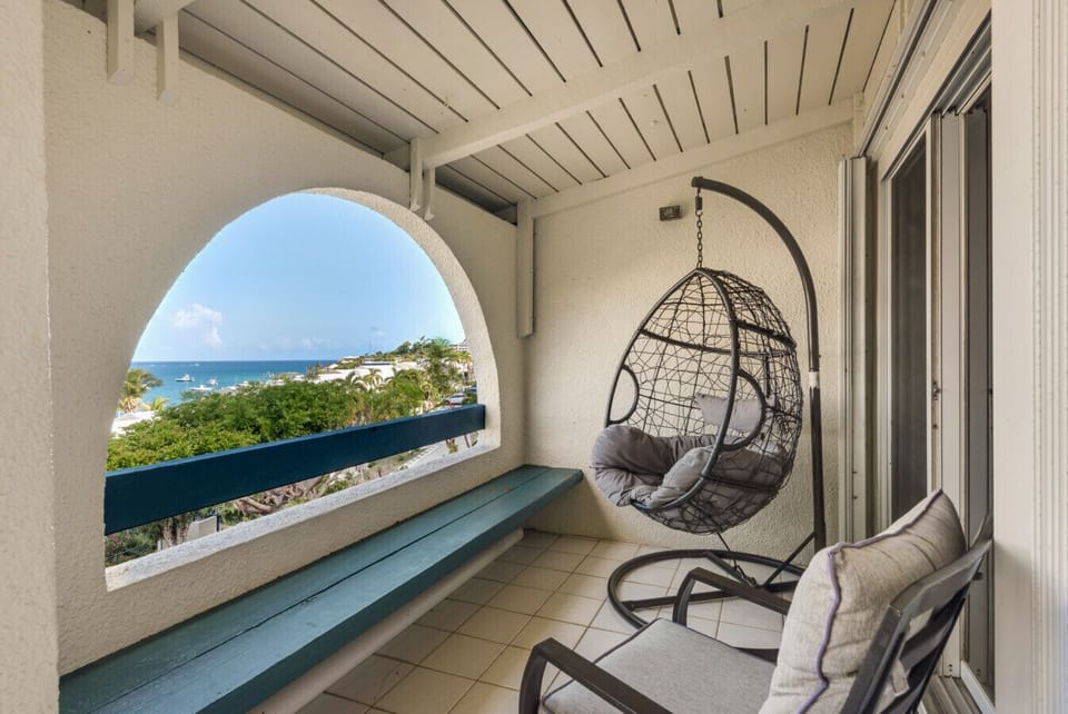 A private balcony with sweeping Caribbean views and a statement egg chair.