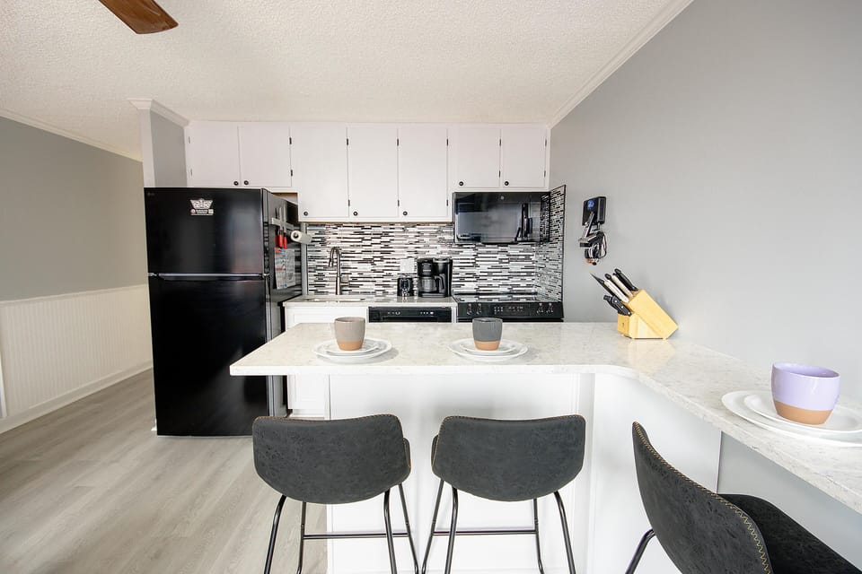 This modern, fully equipped kitchen boasts updated cabinets and a beautiful backsplash.