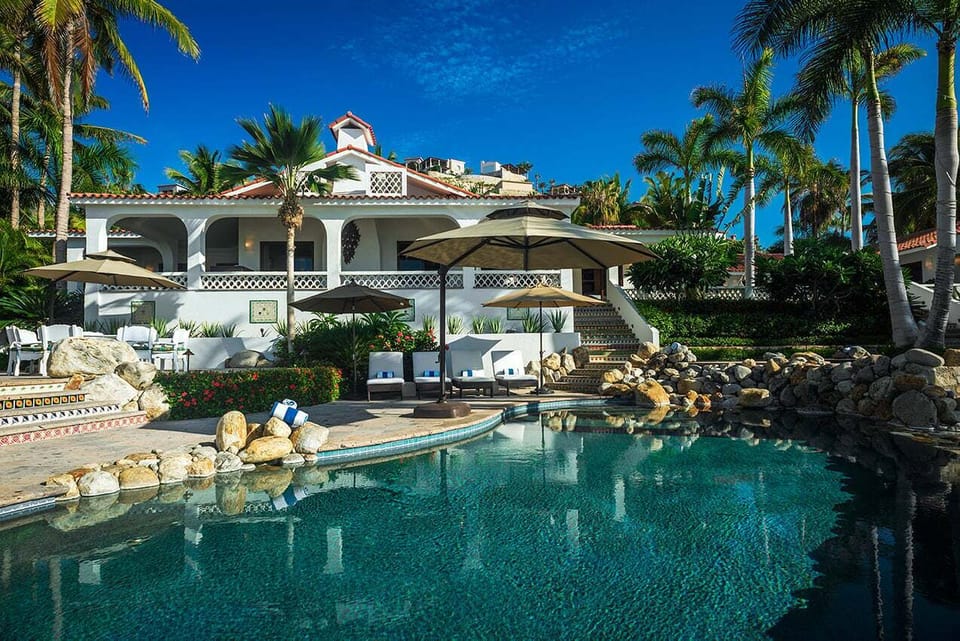Free-form swimming pool with rock waterfall and the main house at Casa Edwards, beachfront villa in Palmilla, Los Cabos