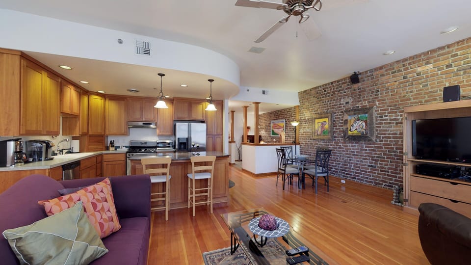 another view of kitchen, living and dining room with tv and recliner chair.