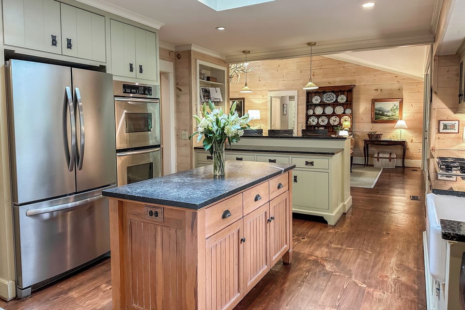 The kitchen features custom cabinetry, soapstone countertops, TV, and coffee bar
