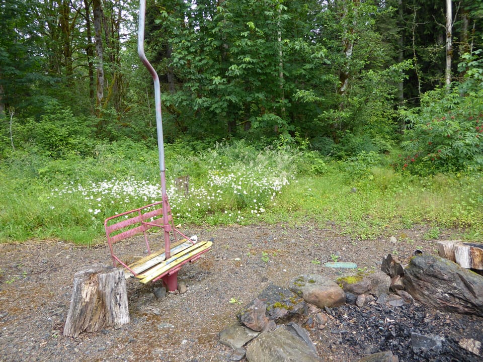 Fire pit outside cabin door with ski lift chair, room to enjoy evening S'mores.