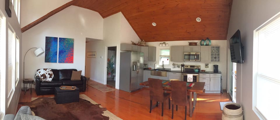 Panoramic view of open concept living area with large wall mount smart TV.