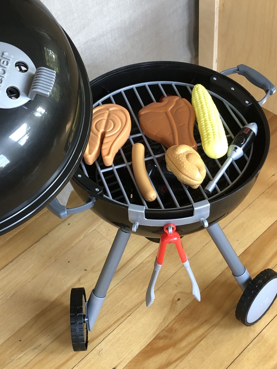 Adorable kid's Weber Grill, complete with food, tongs and a lighter.