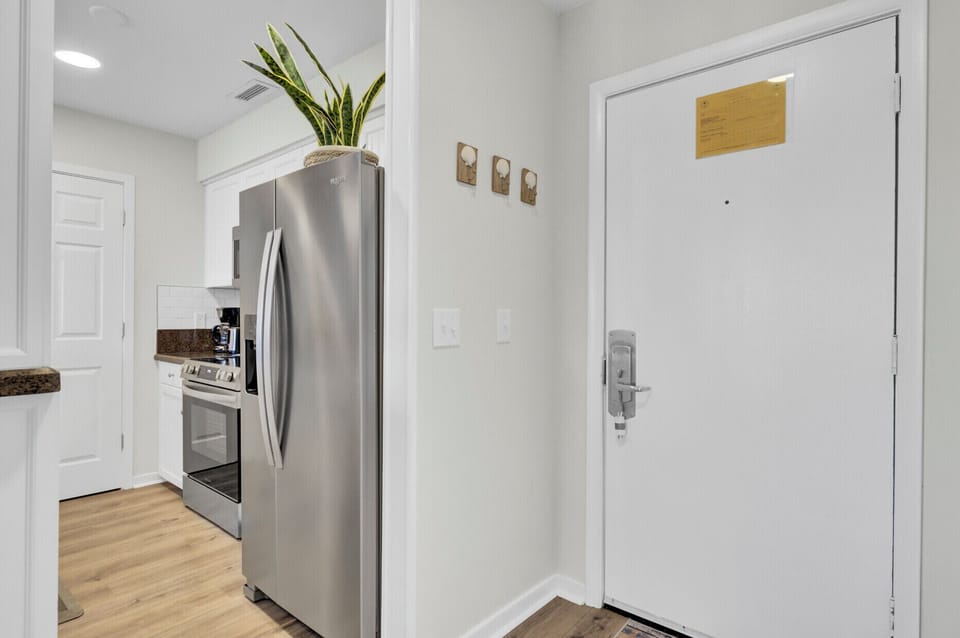 - Step into a bright, welcoming space with immediate access to kitchen essentials - Stainless steel fridge and sleek floors lead the way to a seamless stay - Handy wall hooks and a clean layout make unpacking and settling in effortless