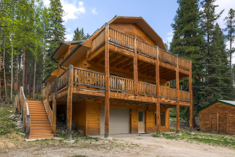 Three story house surrounded by pines.