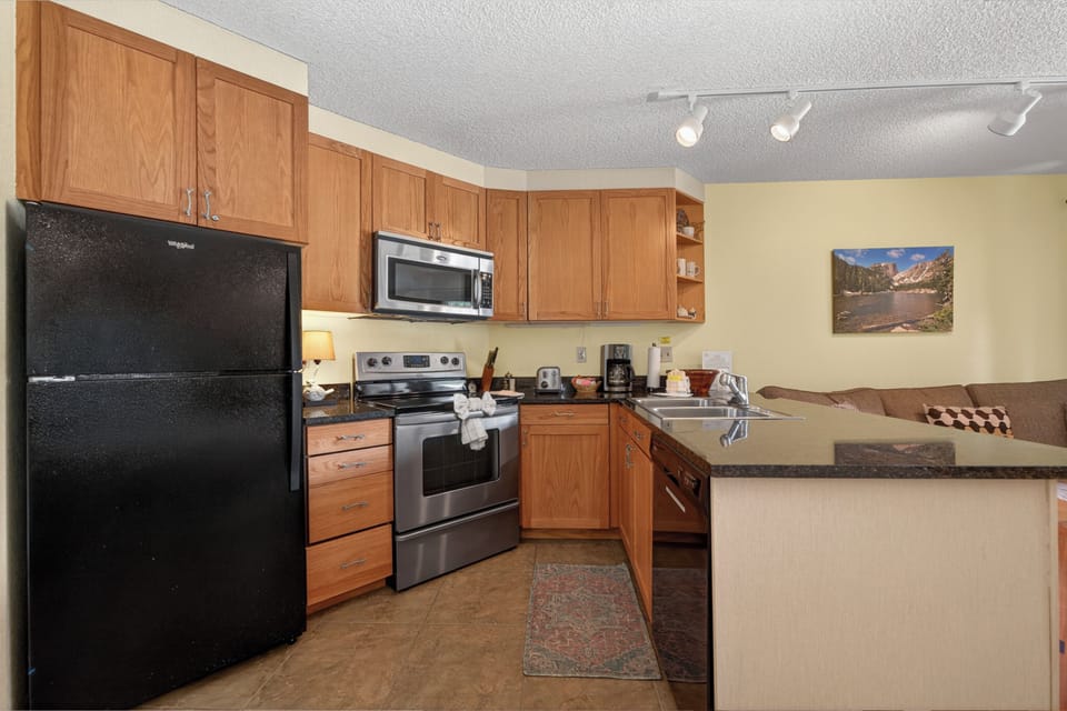 Your fully equipped kitchen features warm wood cabinetry, modern appliances, and a breakfast bar—perfect for preparing home-cooked meals during your mountain getaway.