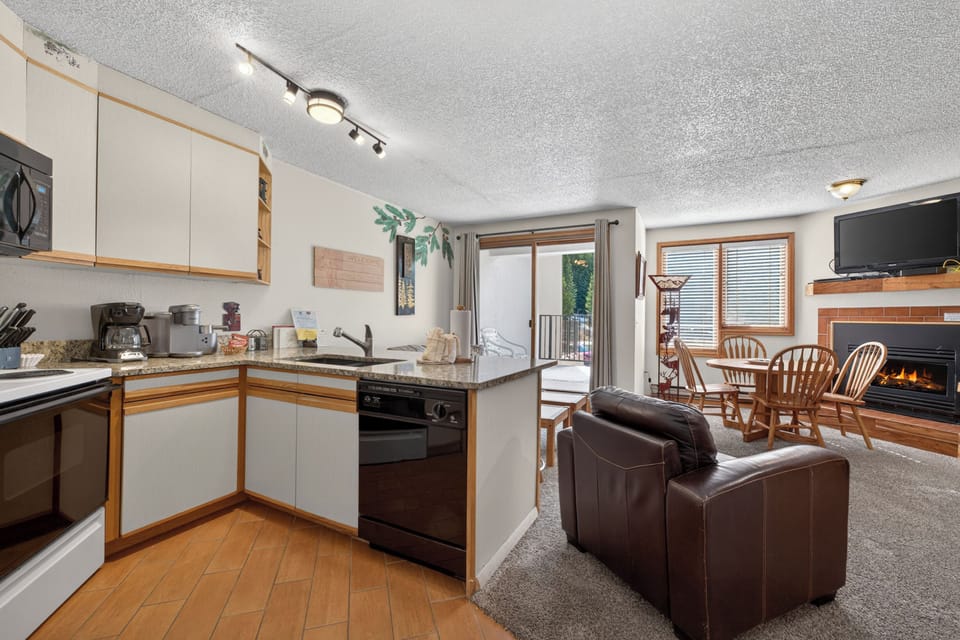 Your cozy open-concept space invites you to cook, relax by the fireplace, and enjoy the natural light streaming through the balcony doors.