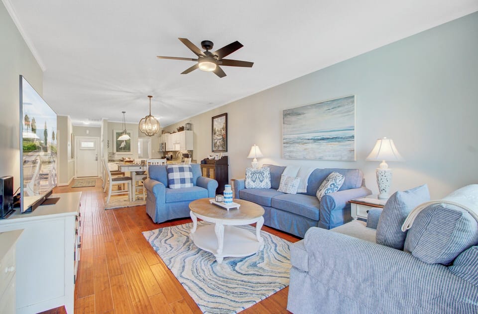 Sink into coastal comfort in your spacious living area, where soft blue furnishings and ocean-inspired artwork create the perfect beach retreat.