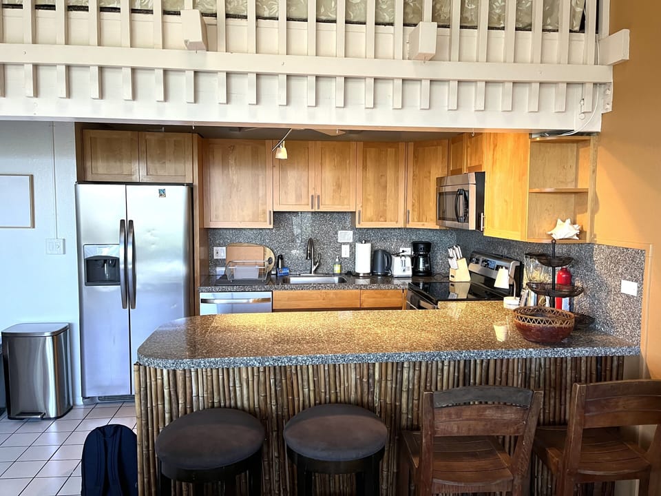 Kitchen area with chairs for sitting at the bar.