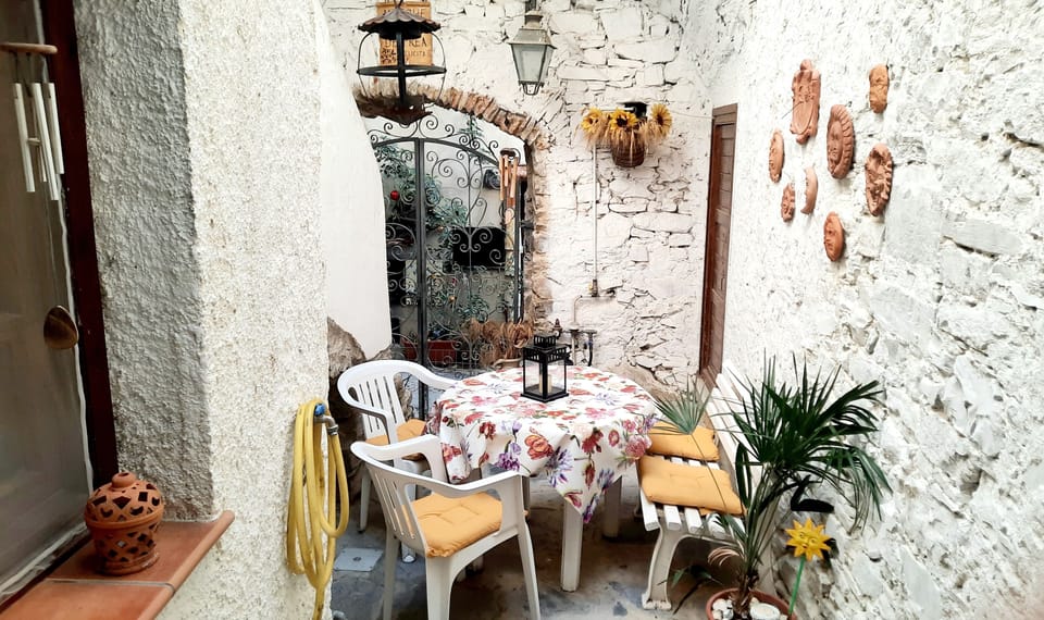 Cortile attrezzato, circondato dalle case in pietra, vista su vicolo pedonale.