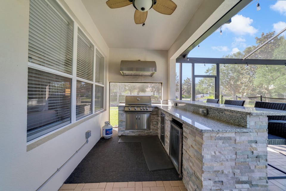 Outside kitchen with large gas BBQ grill and 65" TV.
