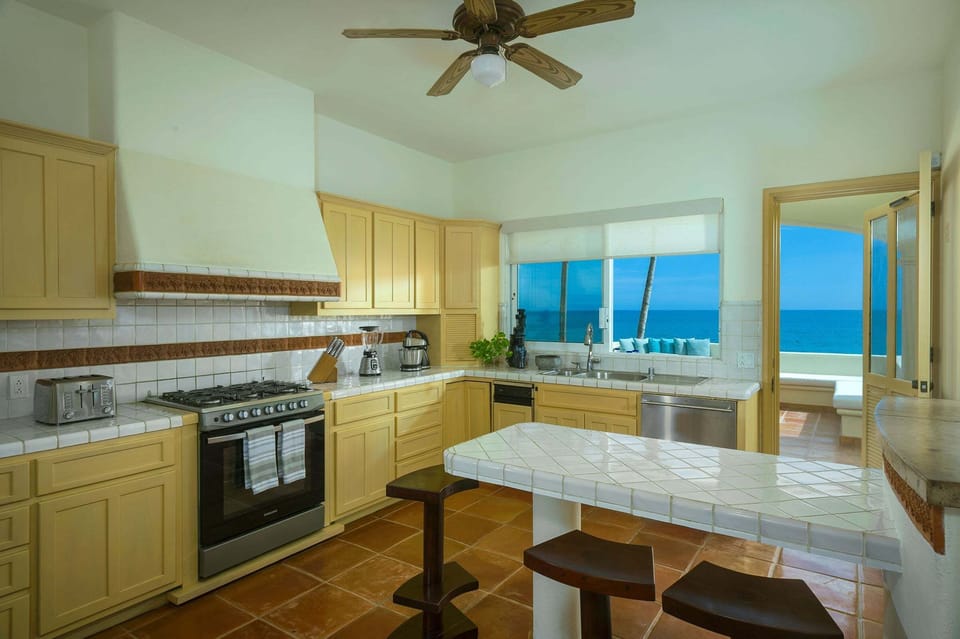 Fully equipped integrated kitchen with an island, luxury appliances, and a window facing the sea.