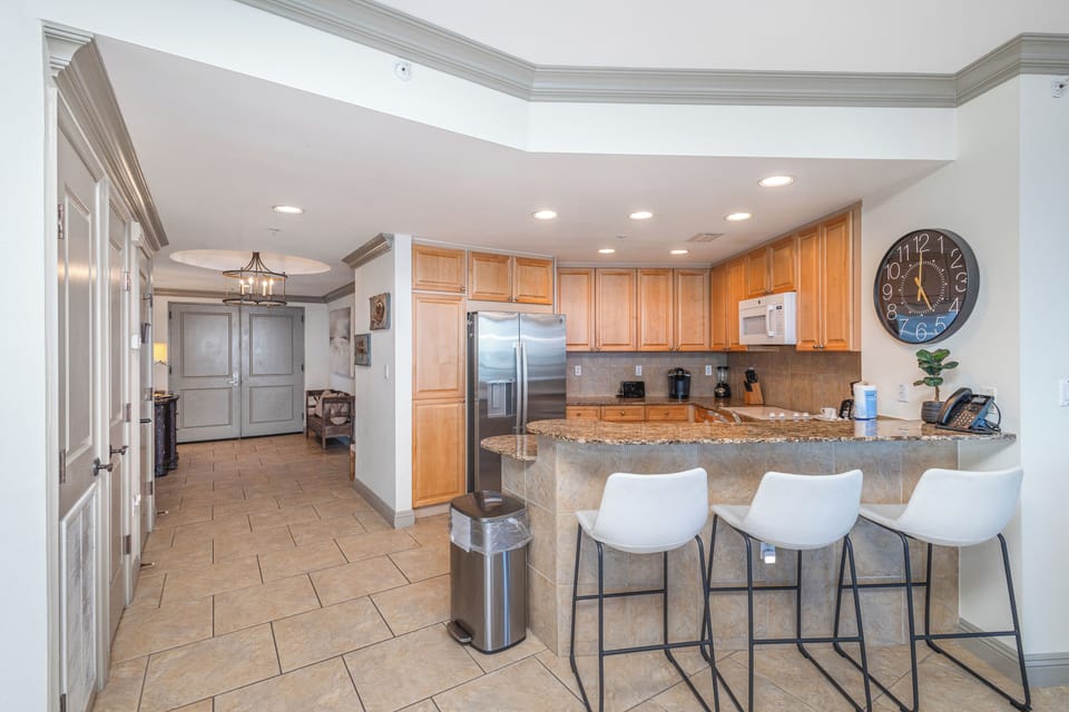 Step into your fully equipped kitchen, perfect for preparing meals with granite countertops, modern appliances, and a breakfast bar where you can enjoy morning coffee together.